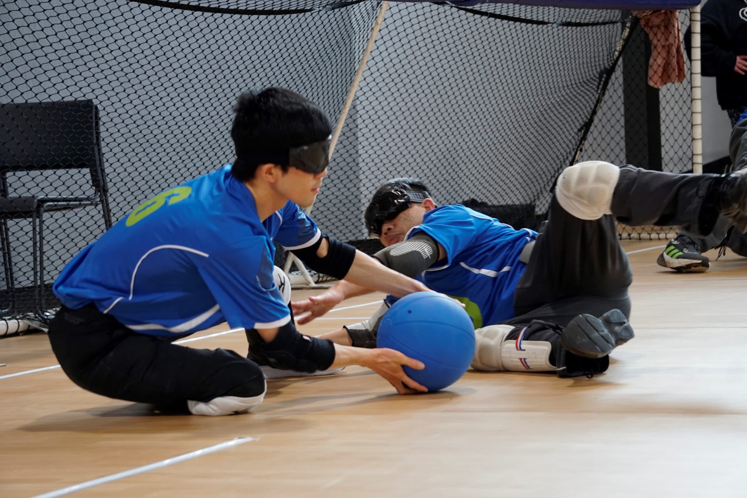 Two athletes with low vision playing goalball.